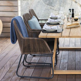 Donkere gevlochten stoelen aan een houten tafel