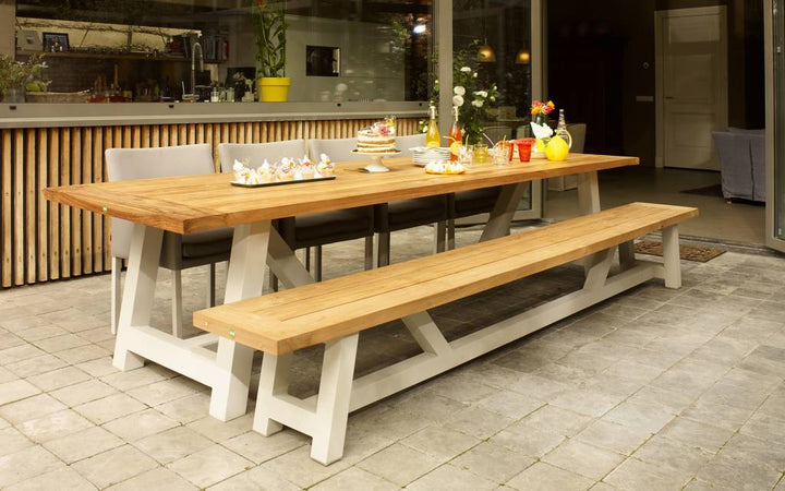 Houten tuintafel met lange banken op een betegeld terras