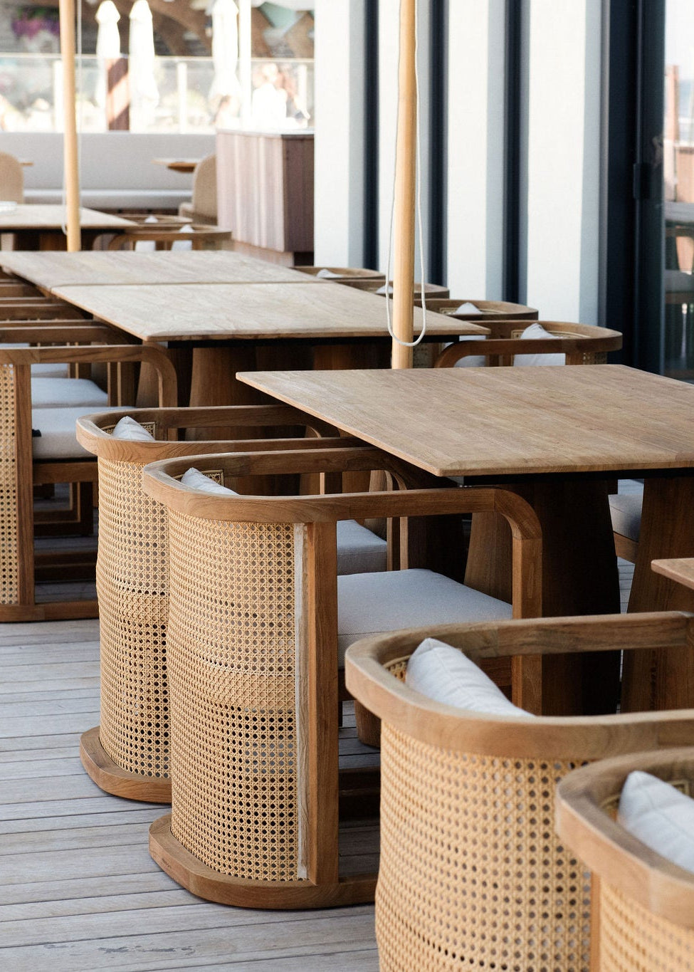 Terrastafels en gevlochten stoelen bij een horecalocatie, voor zakelijk terrasmeubelonderhoud.