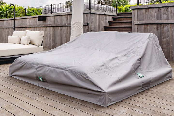 Grijze beschermhoes over een loungeopstelling op een terras