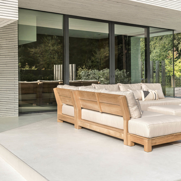 Houten loungebank met lichte kussens op een terras
